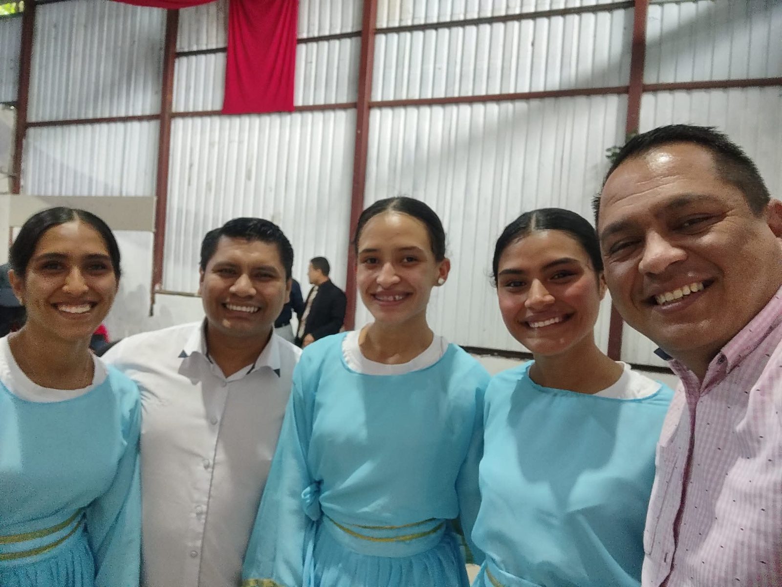 Danzarinas de Kemuel con vestuario turquesa sonriendo junto a dos acompañantes