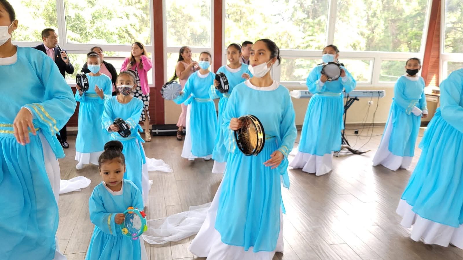 Grupo de danzarinas de diferentes edades con vestuario turquesa y panderos